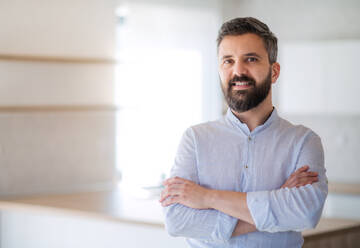 Mature man standing in house, looking at camera. A moving in new home concept. - HPIF21159