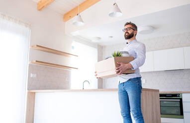 Low angle view of mature man with box moving in new unfurnished house. Copy space. - HPIF21161