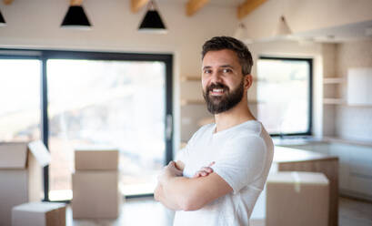 Mature man standing in house, looking at camera. A moving in new home concept. - HPIF21188