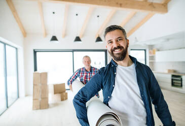 A cheerful senior man helping his mature son with furnishing new house, a new home concept. - HPIF21295