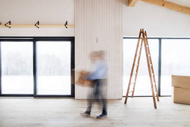 An unrecognizable man walking with cardboard boxes when furnishing new house. Intentional motion blur. - HPIF21307