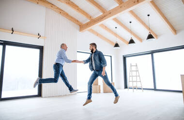 Ein fröhlicher reifer Mann, der mit seinem älteren Vater in einem neuen Haus springt, ein neues Hauskonzept. - HPIF21312