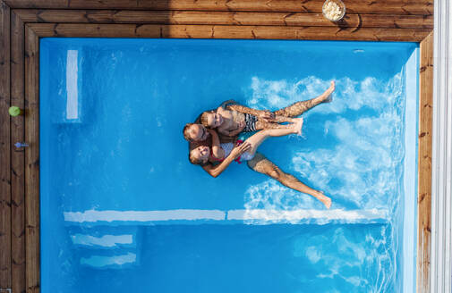 Top view of father with two small children sitting in swimming pool outdoors. - HPIF21332