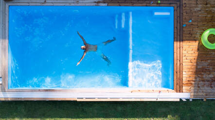 Draufsicht auf einen Mann, der in einem Schwimmbad im Freien im Wasser schwimmt. - HPIF21336