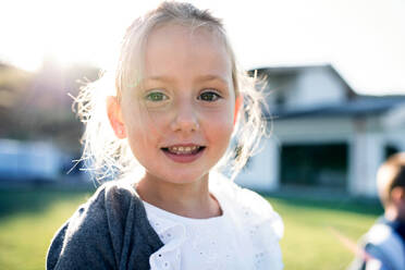 A front view of small girl standing outdoors, looking at camera. - HPIF21339