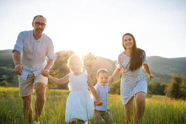 Happy young family with two small children running on meadow outdoors at sunset. - HPIF21349