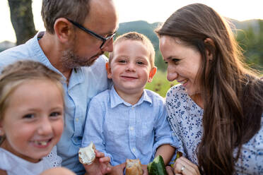 Eine junge Familie mit zwei kleinen Kindern auf einer Wiese im Freien beim Picknick. - HPIF21359