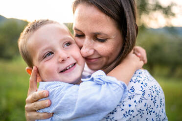 A mother with small toddler son on walk on meadow outdoors, hugging. - HPIF21362