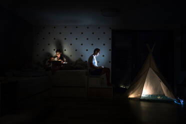 Junge Familie mit Kindern sitzt im Schlafzimmer und benutzt einen Laptop. - HPIF21370