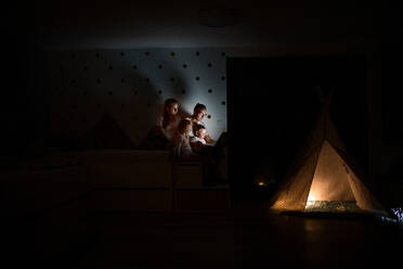 A family with children sitting indoors in bedroom, using laptop. - HPIF21374