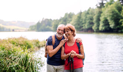 Ein älteres Touristenpaar auf einem Spaziergang in der Natur, stehend am See. Kopierraum. - HPIF21393
