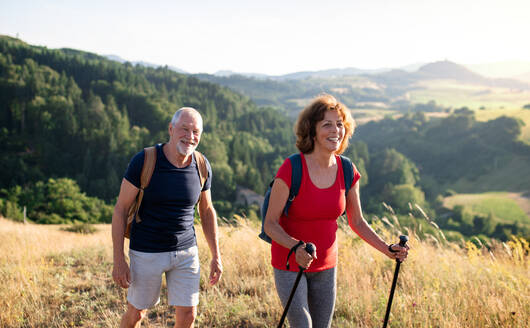 A senior tourist couple travellers hiking in nature, walking. - HPIF21402