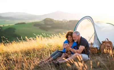 Ein älteres Paar genießt den Sonnenuntergang in der Natur, während es ein Selfie mit seinem Smartphone macht - HPIF21409