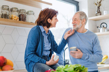 Ein Porträt eines verliebten, glücklichen älteren Paares, das zu Hause Kaffee trinkt. - HPIF21437
