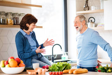 A senior couple in love indoors at home, man giving flowers to happy woman. - HPIF21439