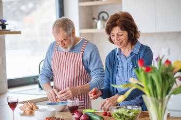 Ein Porträt eines glücklichen, verliebten älteren Paares zu Hause beim Kochen. - HPIF21458