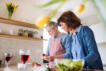 Ein Porträt eines glücklichen, verliebten älteren Paares zu Hause beim Kochen. - HPIF21459