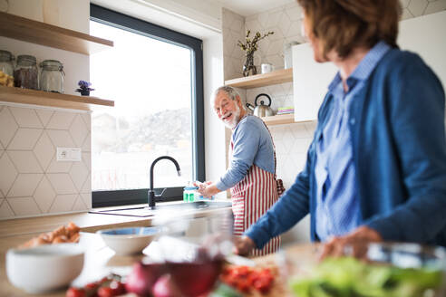 Ein Porträt eines glücklichen älteren Paares zu Hause beim Kochen. - HPIF21462