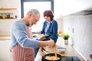 Ein Porträt eines glücklichen, verliebten älteren Paares zu Hause beim Kochen. - HPIF21466