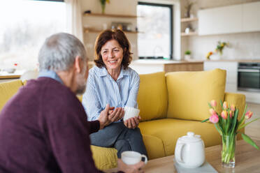 Ein verliebtes älteres Paar, das zu Hause auf dem Sofa sitzt und sich unterhält. - HPIF21497