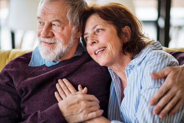 Ein verliebtes älteres Paar, das zu Hause auf dem Sofa sitzt und sich unterhält. - HPIF21500