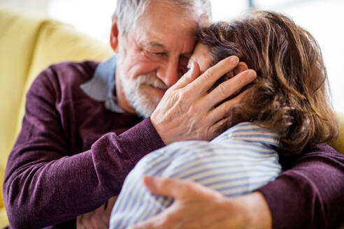 Ein verliebtes älteres Paar, das zu Hause auf dem Sofa sitzt und sich umarmt. - HPIF21501