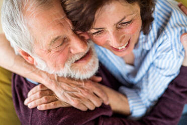 Draufsicht auf ein verliebtes älteres Paar, das zu Hause auf dem Sofa sitzt und sich umarmt. - HPIF21502