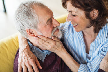 Ein verliebtes älteres Paar, das zu Hause auf dem Sofa sitzt und sich unterhält. - HPIF21504