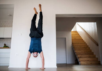 Ein älterer Mann, der zu Hause Handstandübungen macht, kopiert den Raum. - HPIF21524