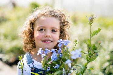 Portrait of cute small girl standing in the backyard garden. Copy space. - HPIF21557