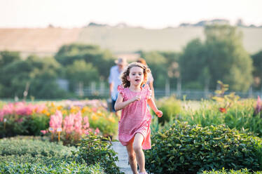 A front view of small girl running in the backyard garden. - HPIF21617