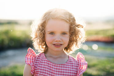 Portrait of cute small girl standing in the backyard garden, looking at camera. - HPIF21618