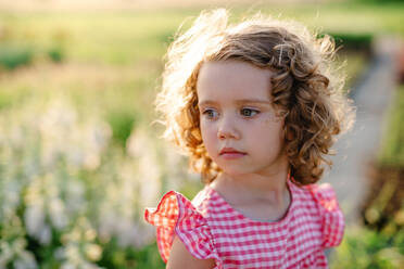 Portrait of cute small girl standing in the backyard garden. Copy space. - HPIF21619