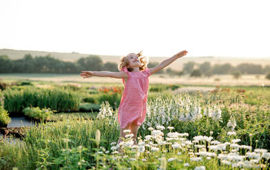 Cheerful small girl running in the backyard garden, having fun. Copy space. - HPIF21621