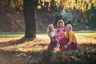 Portrait of small girl with mother and grandmother resting in autumn forest. - HPIF21645