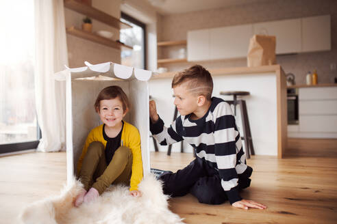 Zwei glückliche kleine Kinder spielen zu Hause im Haus. - HPIF21677