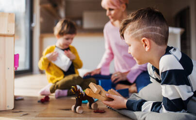 Eine junge Frau mit zwei Kindern, die auf dem Boden mit Spielzeug spielen. - HPIF21688