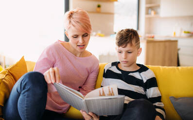 Eine junge Frau mit einem kleinen Sohn sitzt zu Hause und liest ein Buch. - HPIF21692