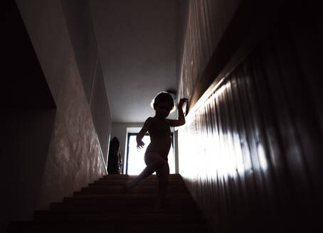 Eine Silhouette eines kleinen Kindes, das die Treppe hinuntergeht. - HPIF21719