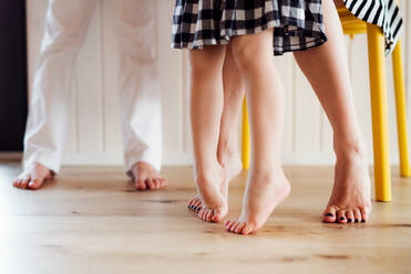 Legs and bare feet of young woman with two children standing at home. - HPIF21725