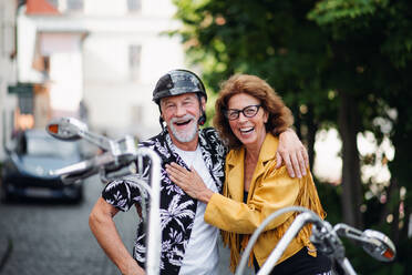 Frontansicht eines fröhlichen älteren Ehepaars, das mit dem Motorrad durch die Stadt reist. - HPIF21779