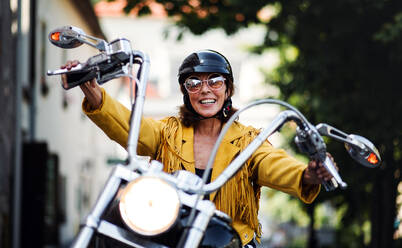 Eine fröhliche ältere Frau, die mit dem Motorrad in der Stadt unterwegs ist. - HPIF21791