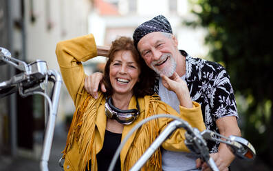 Frontansicht eines fröhlichen älteren Ehepaars, das mit dem Motorrad durch die Stadt reist. - HPIF21799