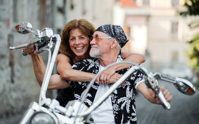 Frontansicht eines fröhlichen älteren Ehepaars, das mit dem Motorrad durch die Stadt reist. - HPIF21806