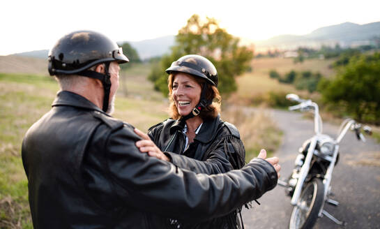 Ein fröhliches älteres Ehepaar reist mit dem Motorrad auf dem Land und unterhält sich. - HPIF21811