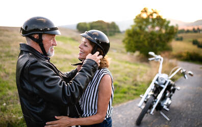 Frontansicht eines fröhlichen älteren Paares, das verliebt mit dem Motorrad durch die Landschaft reist. - HPIF21813
