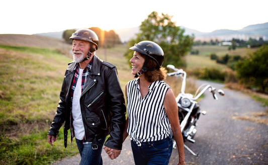 Frontansicht eines fröhlichen älteren Paares, das mit dem Motorrad auf dem Land unterwegs ist. - HPIF21814