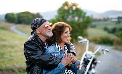 Frontansicht eines fröhlichen älteren Paares, das mit dem Motorrad auf dem Land unterwegs ist. - HPIF21838