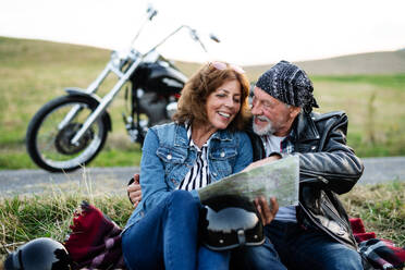 Ein fröhliches älteres Ehepaar reist mit Karte und Motorrad durch die Landschaft. - HPIF21847