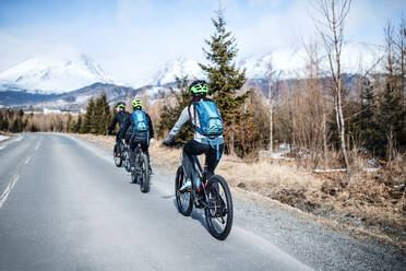 Rückansicht einer Gruppe von Mountainbikern, die im Winter draußen auf der Straße fahren. - HPIF21856